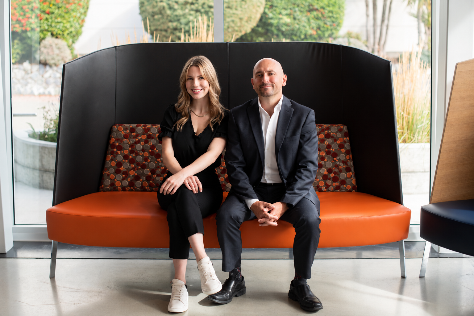Chris Barrington Foote and Maddy McOuatt seated together on an orange sofa